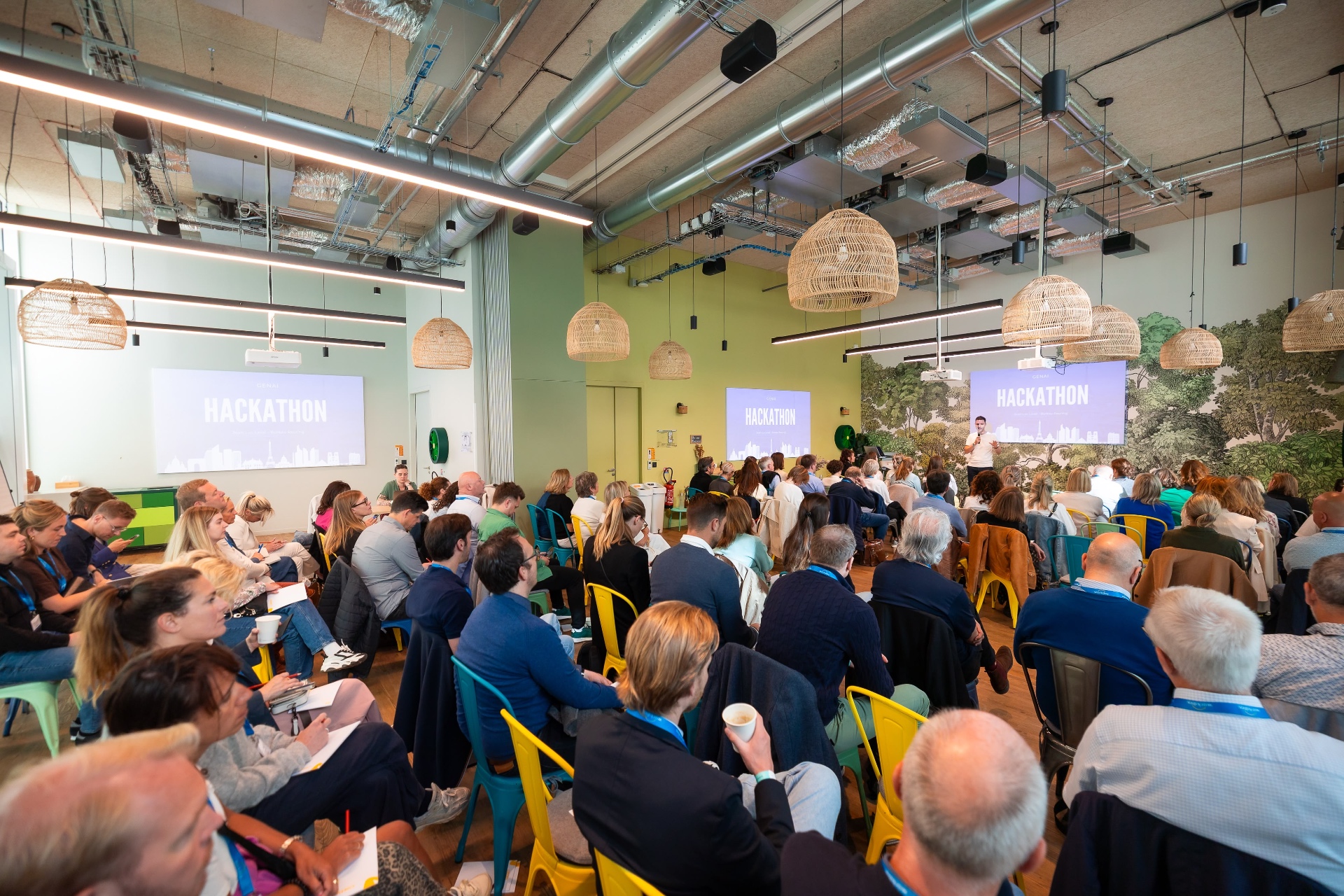 Hackathon publiek luistert naar AI presentatie